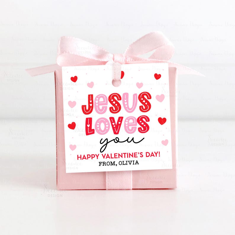 May include: A pink gift box tied with a light pink ribbon and bow. A white tag with red and pink hearts reads "JESUS LOVES you" and "HAPPY VALENTINE'S DAY! FROM, OLIVIA".