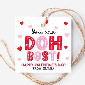May include: A square Valentine's Day gift tag with the message "You are DOH BEST!" in red and pink lettering. The tag is decorated with hearts and the text "Happy Valentine's Day! From, Elysia". A twine string is attached.