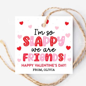 May include: A white Valentine's Day gift tag with the text "I'm so SLAPPY we are FRIENDS!" in red and pink. The tag is decorated with red and pink hearts and has a twine string attached.