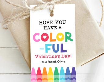 Puede incluir: Una etiqueta de regalo blanca con el mensaje "HOPE YOU HAVE A COLORFUL Valentine's Day!" en letras coloridas. La etiqueta está decorada con ilustraciones de crayones y atada a un regalo envuelto con hilo. La etiqueta está firmada "Your Friend, Olivia."