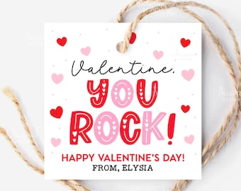 May include: A white Valentine's Day gift tag with red and pink hearts. The tag reads "Valentine, YOU ROCK! HAPPY VALENTINE'S DAY! FROM, ELYSIA" in a playful font. A natural twine loop is attached for hanging.