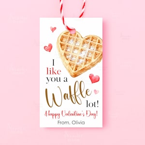 May include: A white gift tag with a watercolor waffle in the shape of a heart, with the text "I like you a Waffle lot! Happy Valentine's Day! From. Olivia". The tag is tied with red and white twine.