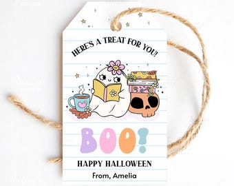 Può includere: Un'etichetta regalo a tema Halloween con un fantasma dei cartoni animati che legge un libro, un teschio e il testo "Here's a treat for you!" e "Happy Halloween". L'etichetta è bianca con linee blu e uno spago marrone.