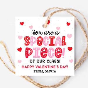 May include: A white Valentine's Day gift tag with a jute string. The tag features the text "You are a SPECIAL PIECE of our class! Happy Valentine's Day! From, Olivia" in red and pink lettering, with heart accents.