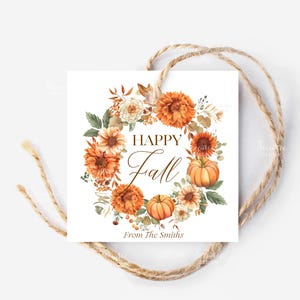 May include: A square gift tag with a watercolour floral wreath in shades of orange, cream, and green, featuring pumpkins and sunflowers. The words "HAPPY Fall" are in the centre, with "From The Smiths" below. A natural twine string is attached.