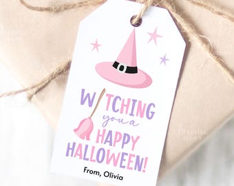 May include: A white gift tag with a pink witch hat, stars, and a broom illustration. The text reads "Witching you a Happy Halloween!" in purple and pink. The tag is tied to a wrapped gift with twine.