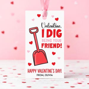 May include: A Valentine's Day gift tag with a red shovel graphic and the text "I DIG BEING YOUR FRIEND!" on a white background. The tag is adorned with red and pink hearts and a pink ribbon. The tag also says "Happy Valentine's Day!" and "From, Olivia."