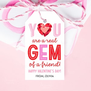 May include: A Valentine's Day gift tag with the message "YOU are a real GEM of a friend!" in pink and red. The tag features a red heart-shaped gem and is tied with pink and white twine.