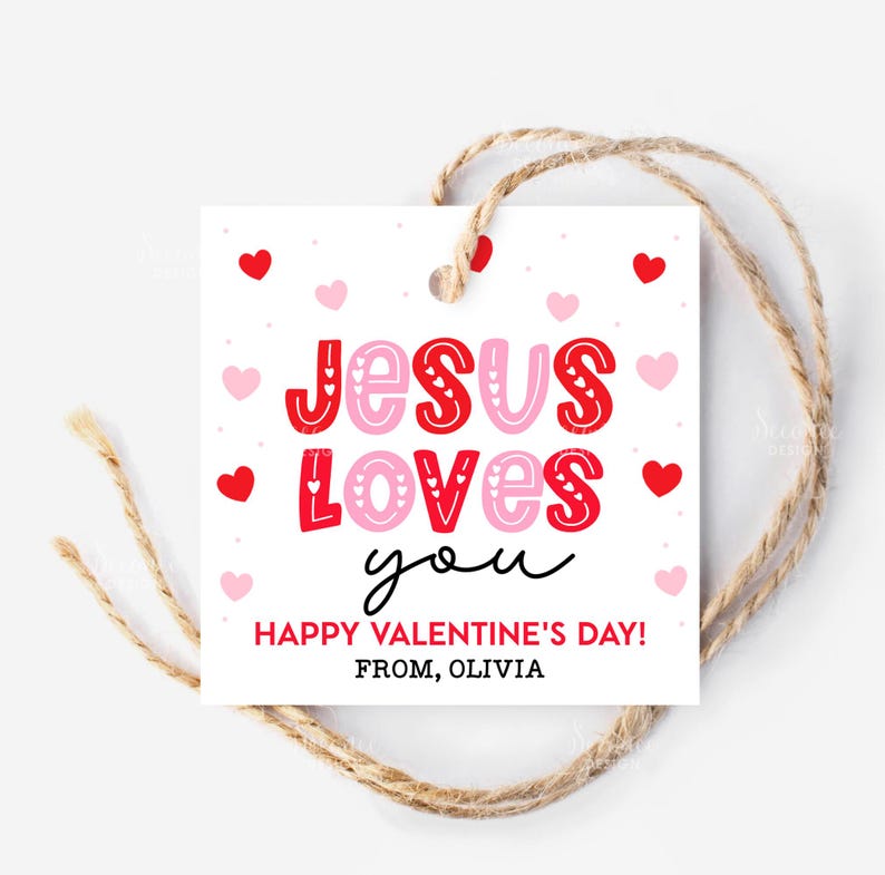 May include: A white Valentine's Day gift tag with the message "Jesus Loves You" in red and pink lettering, surrounded by hearts. The tag includes the text "Happy Valentine's Day! From, Olivia" and is tied with twine.