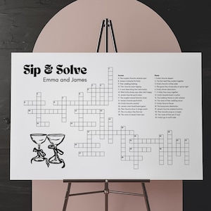 May include: A black and white printable crossword puzzle with the title "Sip & Solve" and the names "Emma and James". The puzzle is on a white background and features two glasses of champagne.