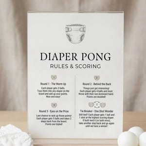 Puede incluir: Un letrero blanco con el texto "DIAPER PONG RULES & SCORING" e ilustraciones de un pañal y un conjunto de reglas. El juego incluye pelotas de ping pong blancas y un pañal.