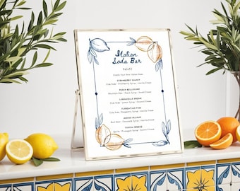May include: A framed sign with the text "Italian Soda Bar" and a menu of soda flavors. The sign is decorated with lemon illustrations and sits on a counter with lemons, oranges, and greenery.