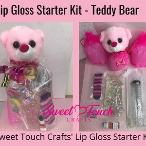 May include: A pink teddy bear lip gloss starter kit. The kit includes a plush teddy bear, lip gloss supplies, and a lollipop. The kit is packaged in clear cellophane with pink accents. The text "Lip Gloss Starter Kit - Teddy Bear" is at the top.