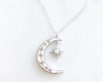 May include: A silver necklace with a crescent moon pendant and a star charm with an iridescent opal stone. The moon pendant is decorated with small stars.