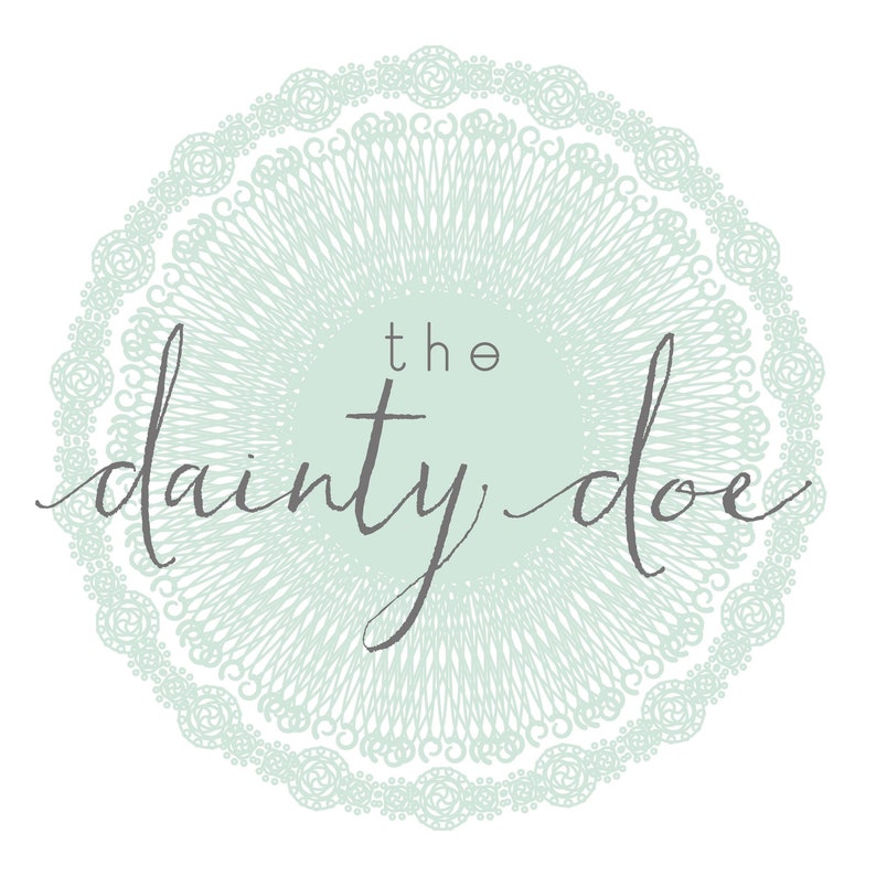 May include: A circular logo design featuring the text "the dainty doe" in a script font. The text is centered within a light green circle, surrounded by a detailed, lace-like border in a matching shade of green, all set against a white background.
