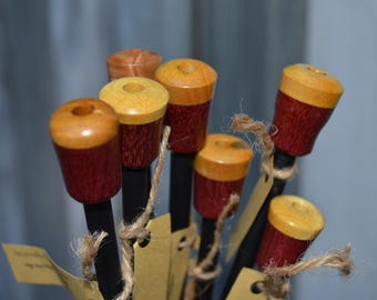 May include: A group of wooden dowels with a red and yellow painted design. The dowels are arranged in a fan shape and are tied together with twine.