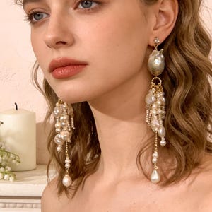 Puede incluir: Pendientes largos de perlas. Cada pendiente presenta una perla grande e irregular en la parte superior, con hilos de perlas más pequeñas y detalles dorados. Un diseño sofisticado, ideal para ocasiones especiales.