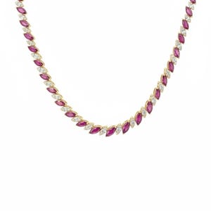 Può includere: Una collana d'oro con pietre preziose di rubino e diamanti a taglio marquise alternati. La collana ha un design delicato con le pietre preziose ravvicinate, creando un motivo continuo di scintillio rosso e bianco.