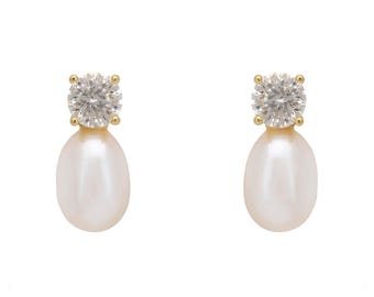 May include: A pair of gold-toned earrings featuring a round, clear gemstone atop a white, teardrop-shaped pearl. The earrings are set against a white background, highlighting the jewelry's elegant design.