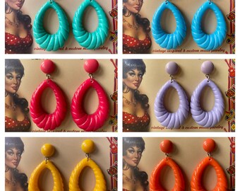 May include: A set of six pairs of vintage-inspired earrings. Each pair features a large, teardrop-shaped earring with a twisted design. The earrings are available in six colors: turquoise, pink, lavender, yellow, orange, and red.