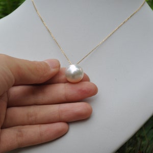 May include: A gold chain necklace with a large, white pearl pendant.