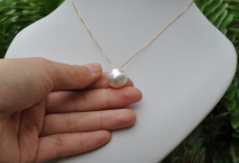 May include: A gold chain necklace with a large, white pearl pendant.