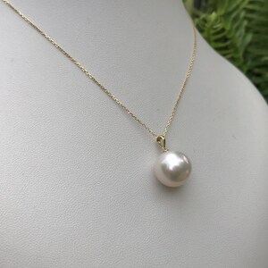 May include: A gold chain necklace with a large, white pearl pendant.