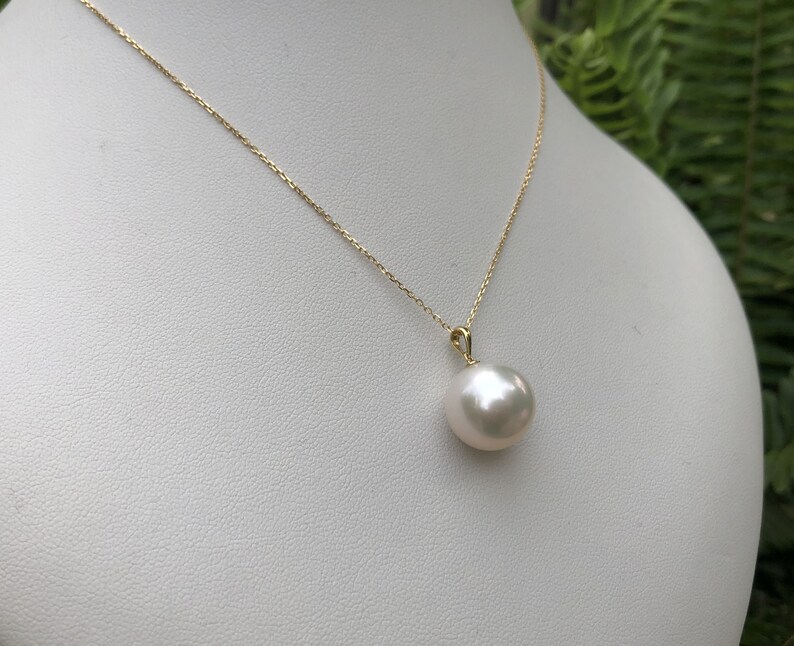May include: A gold chain necklace with a large, white pearl pendant.