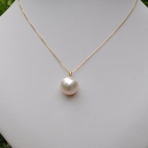 May include: A gold chain necklace with a large, white pearl pendant.