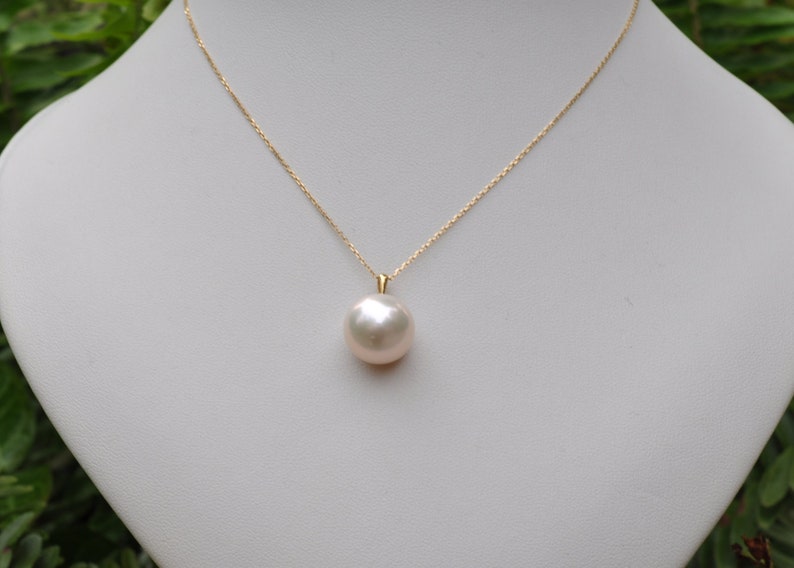 May include: A gold chain necklace with a large, white pearl pendant.
