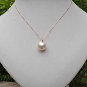 May include: A gold chain necklace with a large, white pearl pendant.