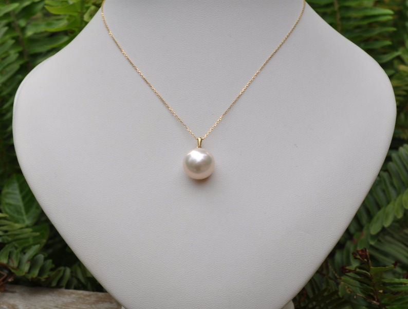 May include: A gold chain necklace with a large, white pearl pendant.