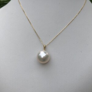 May include: A white pearl pendant necklace with a gold chain. The pearl is round and smooth.