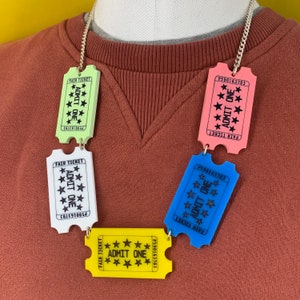 May include: A colorful necklace made of plastic ticket-shaped charms. Each charm is a different color and says "Fair Ticket" and "Admit One" with stars.