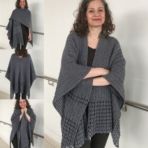 May include: A grey crochet shawl with a lacy pattern. The shawl is draped over a person's shoulders and is worn with a black top and black trousers.