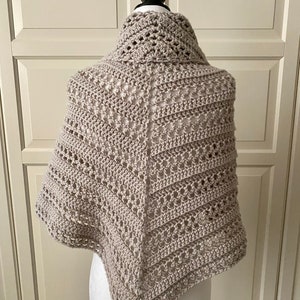 Peut inclure: Un ch&acirc;le en crochet beige avec un motif ajour&eacute;. Le ch&acirc;le est drap&eacute; sur un mannequin.