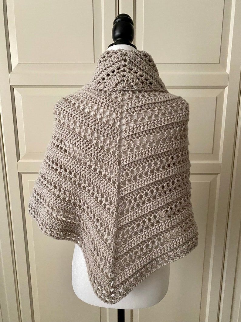 Peut inclure: Un ch&acirc;le en crochet beige avec un motif ajour&eacute;. Le ch&acirc;le est drap&eacute; sur un mannequin.