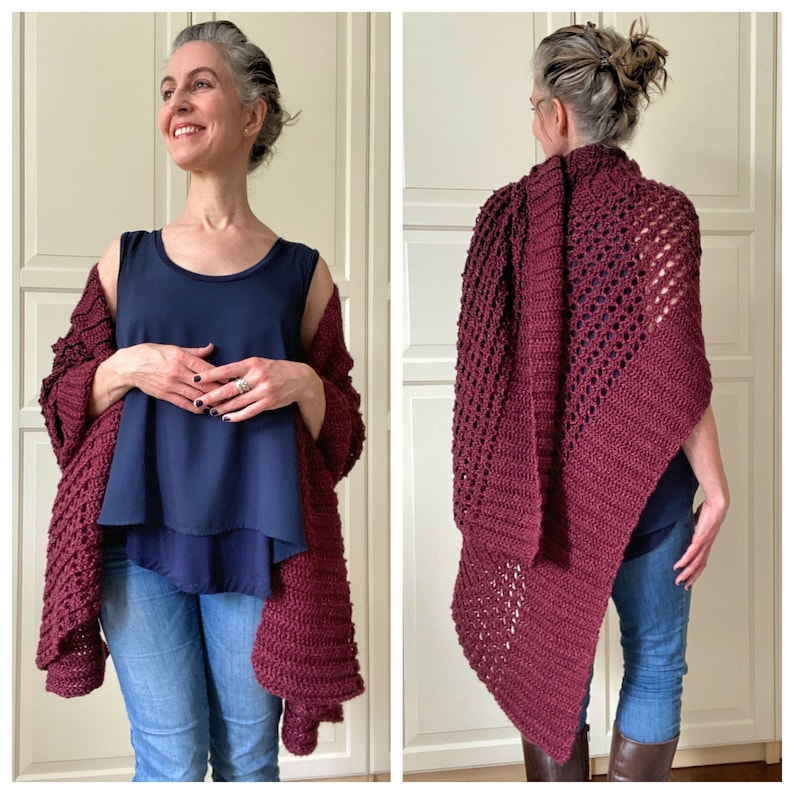 May include: A maroon crocheted shawl with a lacy pattern. The shawl is draped over a person's shoulders and is worn with a navy blue tank top and blue jeans.