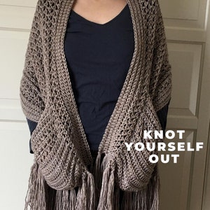 May include: A brown crocheted shawl with fringe and two pockets. The shawl has the text "Knot Yourself Out" printed on it.