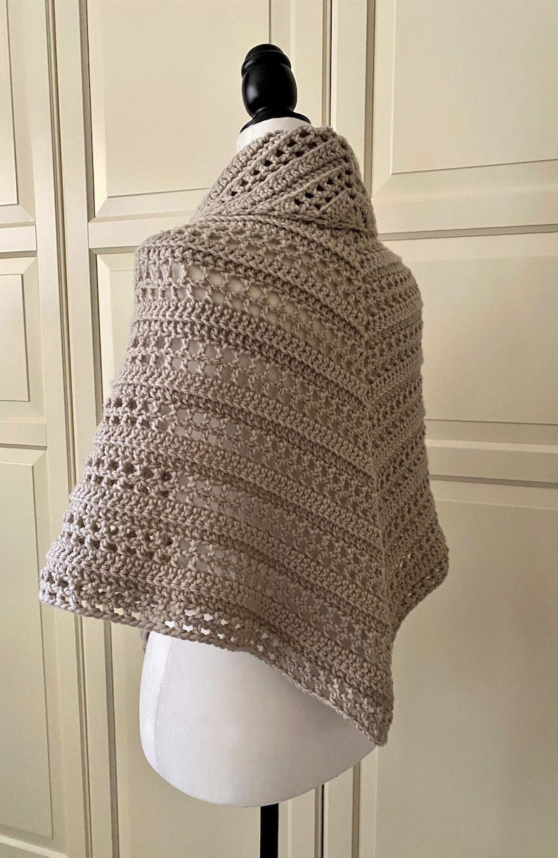 Peut inclure: Un ch&acirc;le en crochet beige avec un motif ajour&eacute; d&eacute;licat. Le ch&acirc;le est drap&eacute; sur un mannequin blanc.