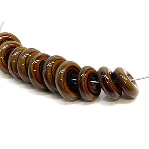 May include: A strand of nine circular, donut-shaped beads featuring a glossy, multi-toned brown and dark amber swirl pattern. Each bead has a smooth, reflective surface and a central hole, strung together on a thin, flexible silver-colored wire.