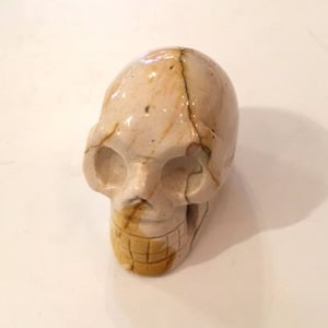 Puede incluir: Una escultura de calavera de piedra tallada en blanco y marrón.