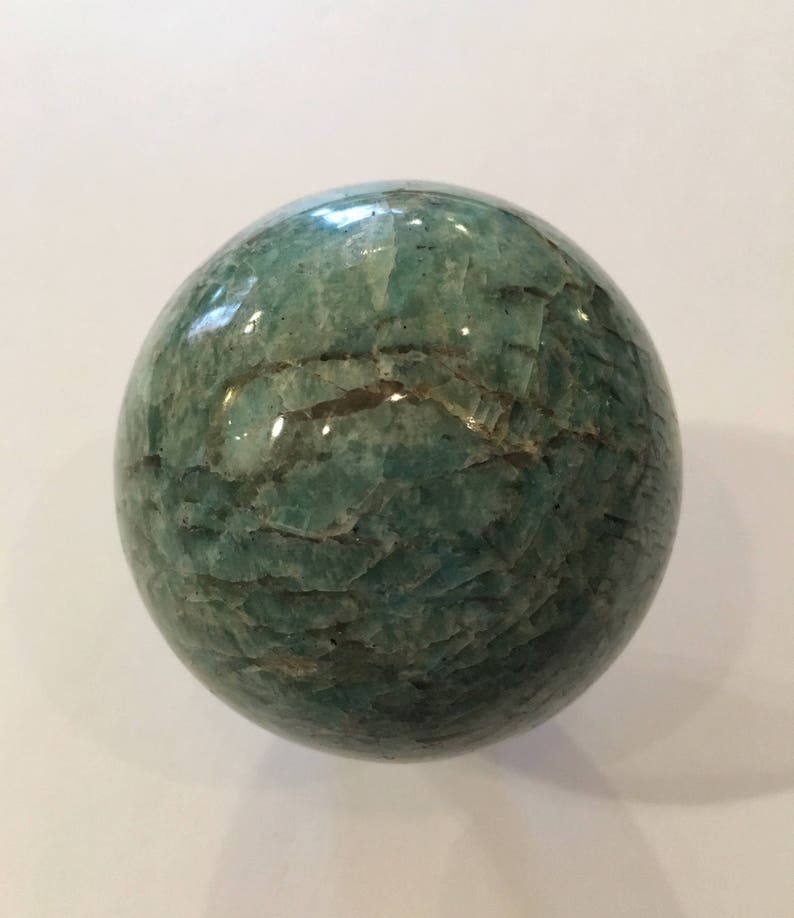 May include: A green aventurine sphere with a smooth, polished surface. The sphere has a natural, marbled pattern with light and dark green hues.