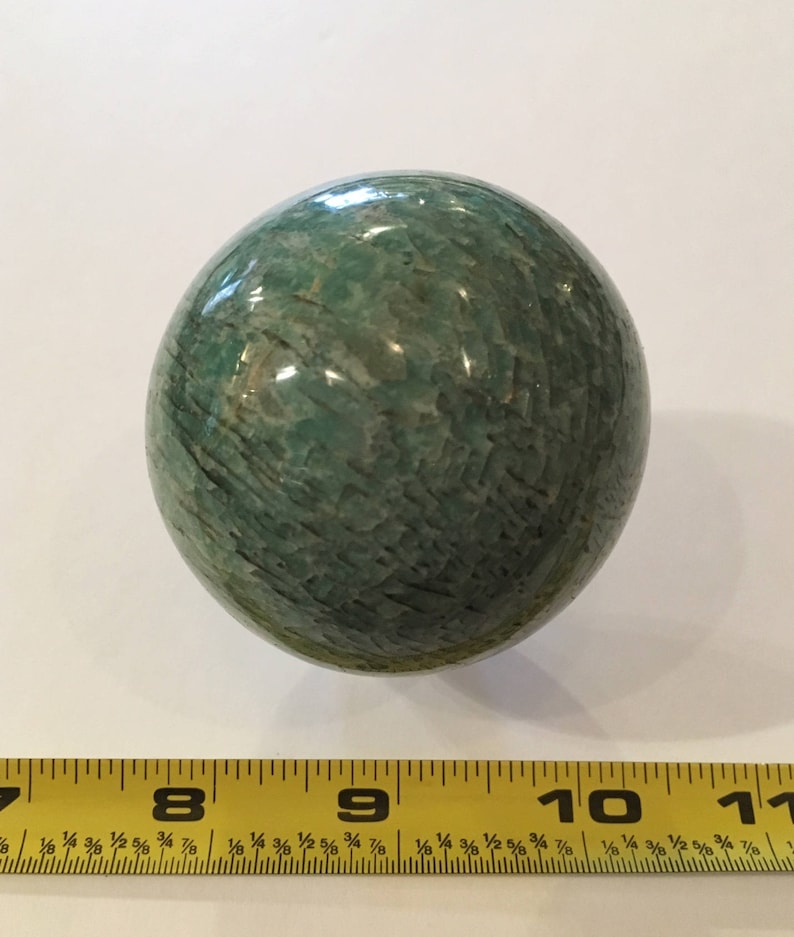 May include: A smooth, green, polished sphere of amazonite, a variety of microcline feldspar, with a diameter of approximately 2.5 inches.