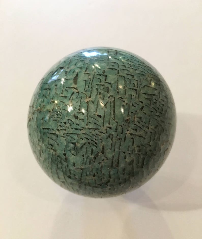May include: A smooth, green sphere with a textured surface. The sphere is made of a material that appears to be jade or a similar stone.