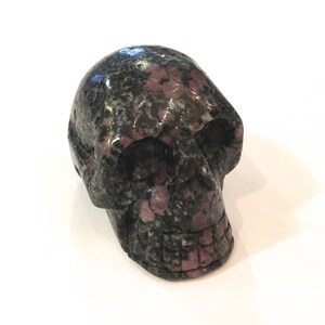 Peut inclure: Une sculpture de crâne en pierre mouchetée de noir et de rose.