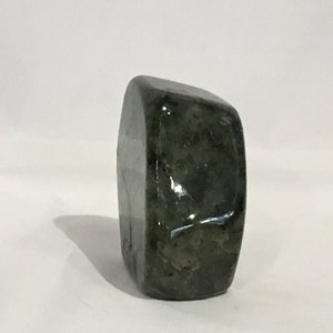 May include: A dark green, irregularly shaped, polished stone with a smooth, glossy surface.