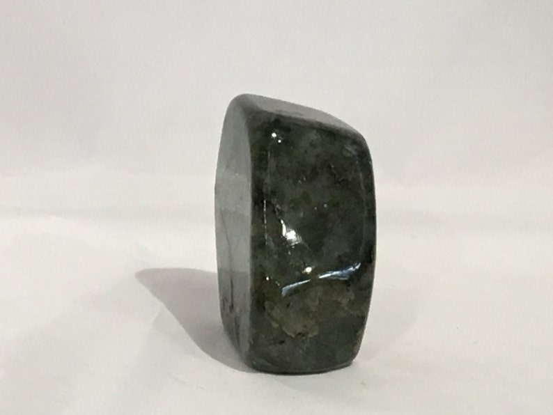 May include: A dark green, irregularly shaped, polished stone with a smooth, glossy surface.