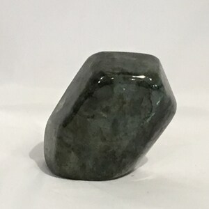 May include: A dark green, irregularly shaped, polished stone with a smooth, glossy surface.