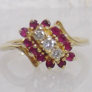 May include: A gold ring with a cluster of small red rubies and clear diamonds set in a swirl design.